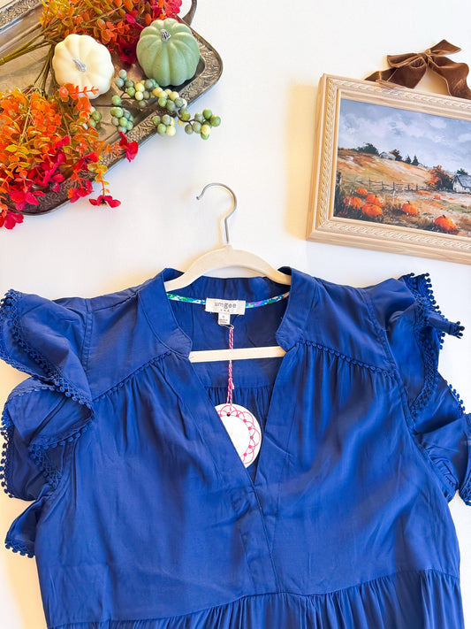 Close-up of navy dress V-neckline and pom pom trimmed flutter sleeves