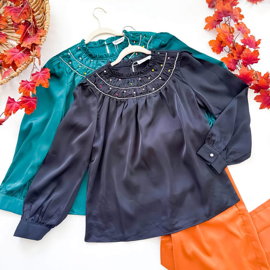 Black and emerald rhinestone satin blouses flat lay